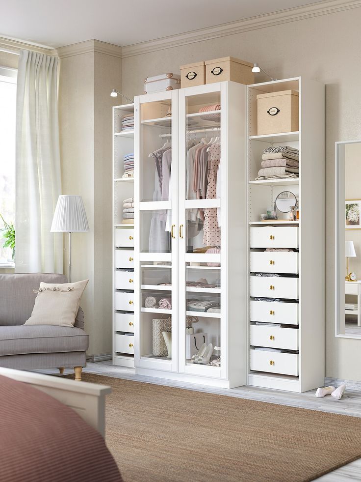 a living room filled with furniture and lots of white storage space next to a window