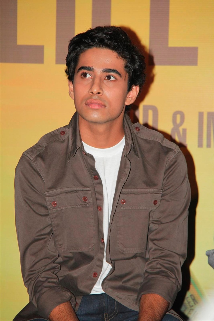 a young man sitting down in front of a yellow sign