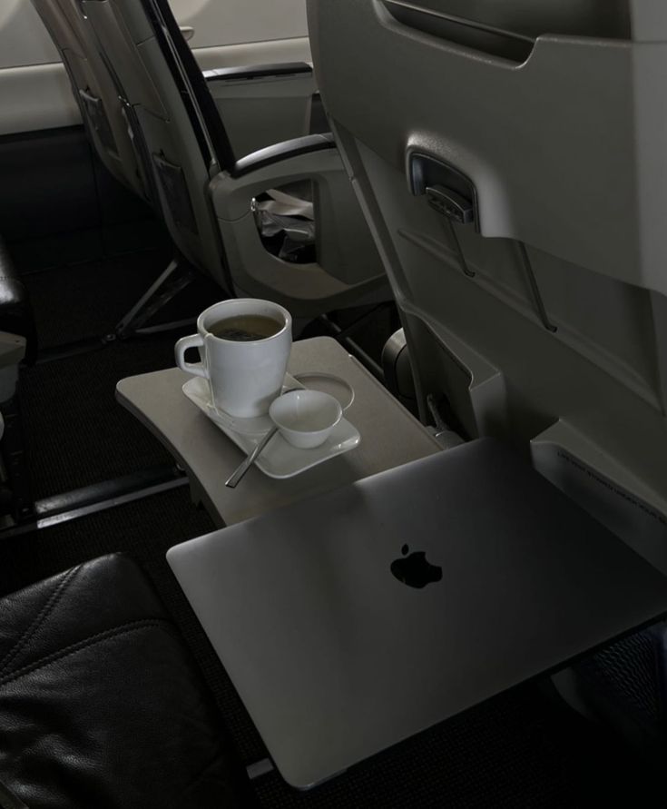 a cup of coffee and a laptop on a table in an airplane