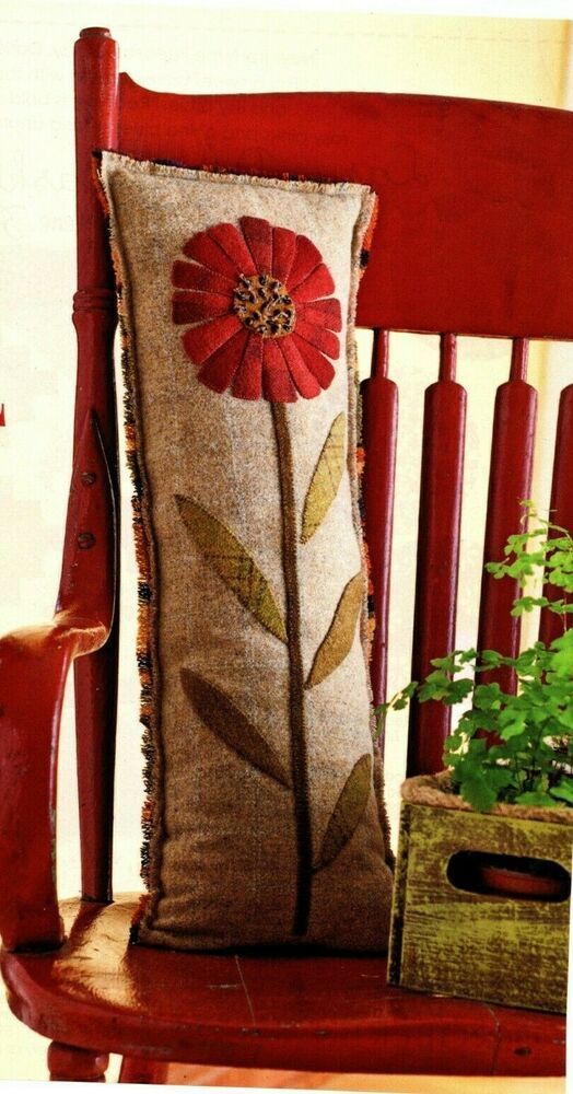 a red chair with a pillow on top of it and a plant in the back