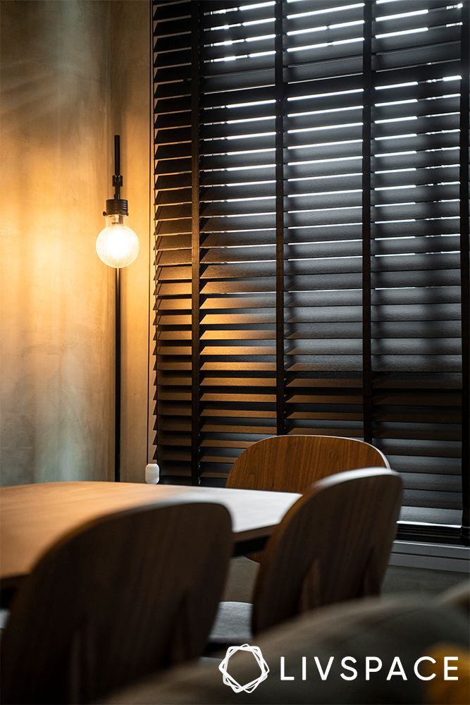 a table and chairs in front of a window with blinds on the wall behind them