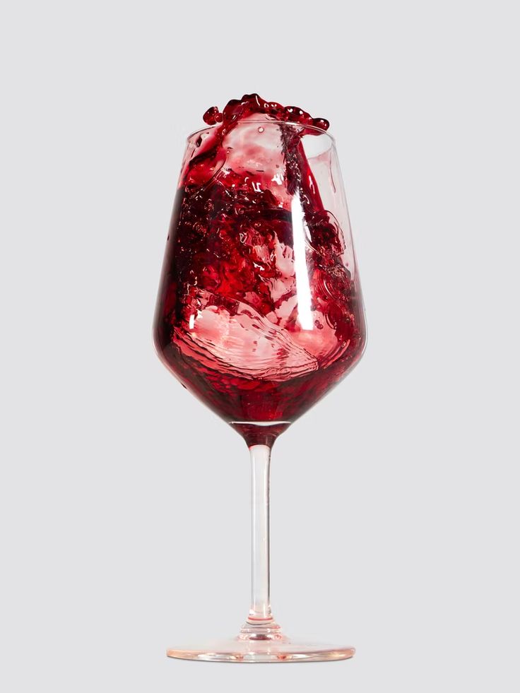 a glass filled with red liquid sitting on top of a table