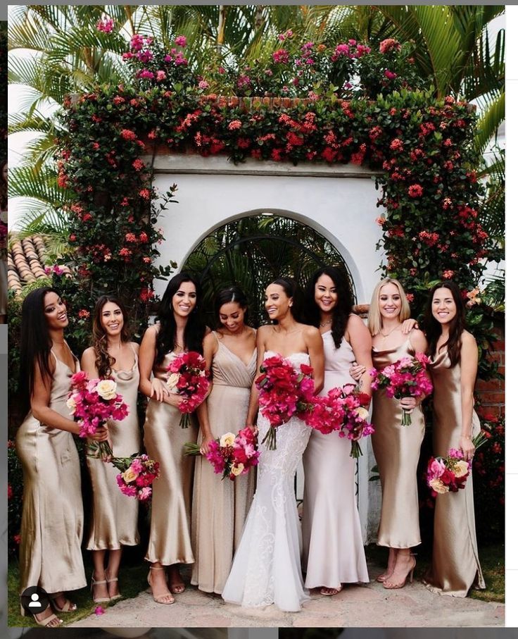 a group of women standing next to each other in front of a flower covered archway