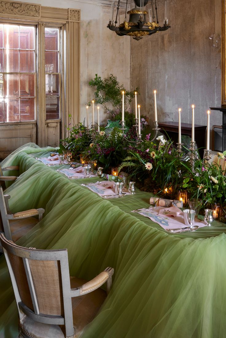 a long table with candles and flowers on it in a dining room next to a fireplace