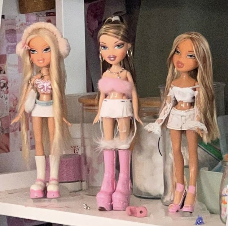 three barbie dolls are standing next to each other on a shelf in a room full of toys