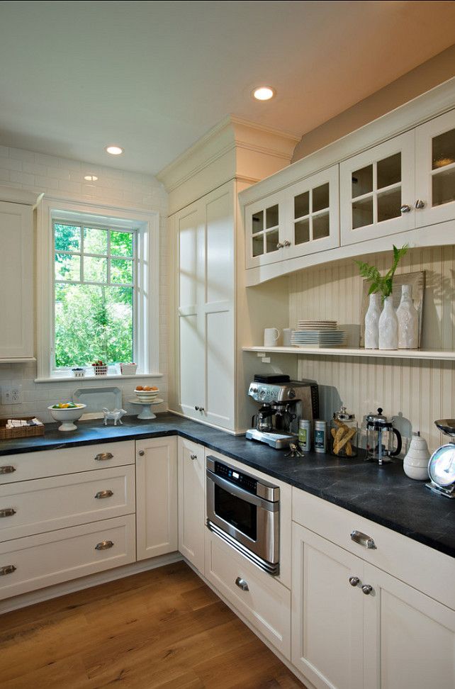 a kitchen with white cabinets and black counter tops