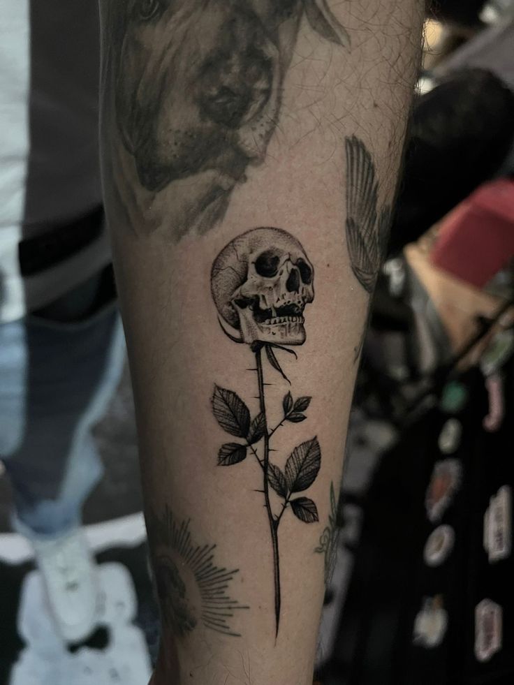 a black and white photo of a skull with a rose on it's leg