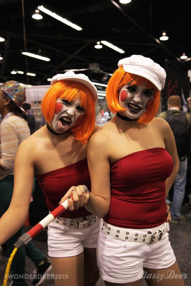 two women dressed up as clowns with orange hair and white make - up on