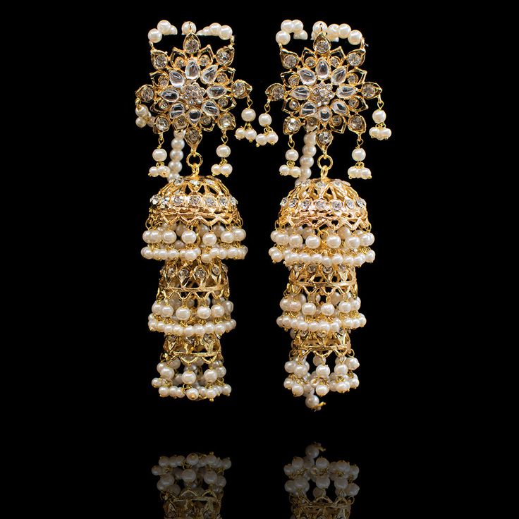 Perfect when you are looking to make a glorious and a majestic impact! Dreamy pair of earrings encrusted with CZ stones and laced with white pearl moti. Approximate earrings length is 4.5". Gold-plated on high-quality brass as the base metal. In-stock & ready-to-ship. *Please Note: We use faux stones and beads in all of our jewelry. Pearl Earrings With Stone Work For Wedding, Wedding Pearl Earrings With Stone Work, Bollywood Style Jeweled Earrings For Reception, Fusion Style White Bridal Earrings With Latkans, Pearl Chandbali Earrings For Receptions, Bollywood Filigree Earrings For Wedding, Festive Pearl Bridal Earrings With Stone Work, White Kundan Pearl Earrings For Reception, Heavy White Chandelier Earrings For Festive Occasions