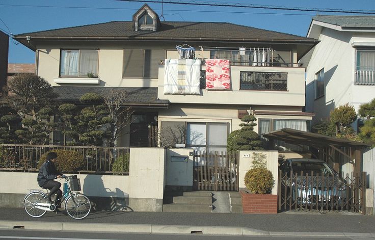 a person riding a bike in front of a house with laundry hanging from the roof