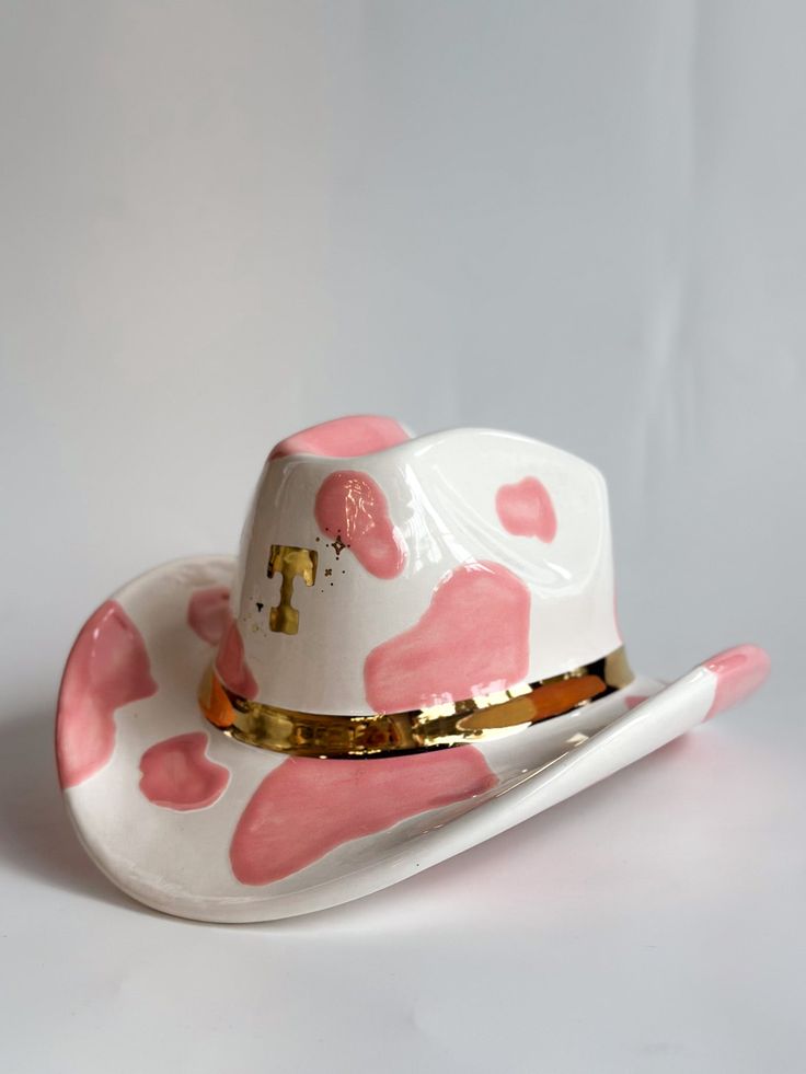 a white hat with pink hearts on it and a gold band around the brim