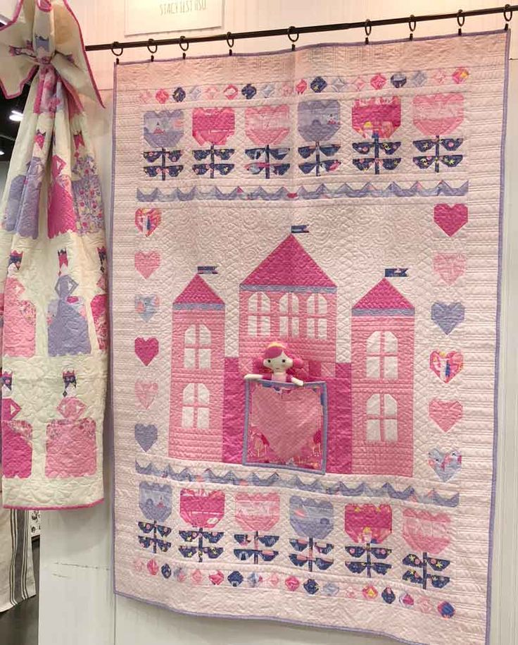 a pink and purple quilt hanging on a wall