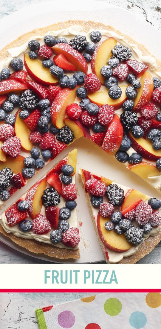 a fruit pizza on a white plate topped with fresh berries and blueberries is cut into slices