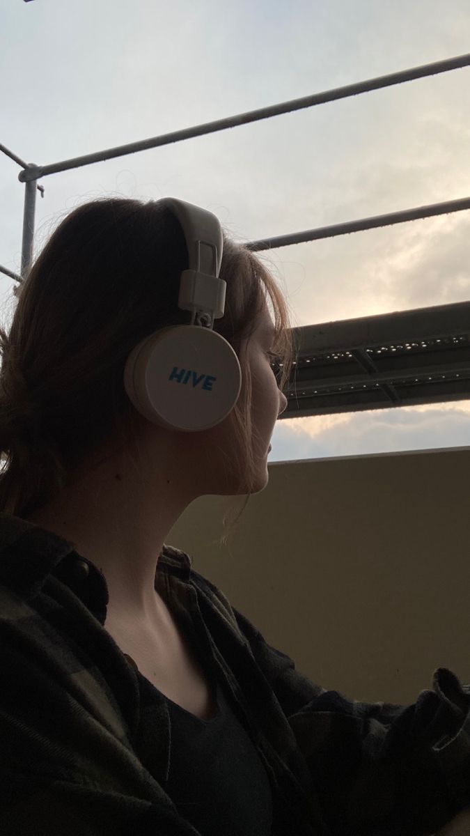 a woman with headphones on looking at the sky