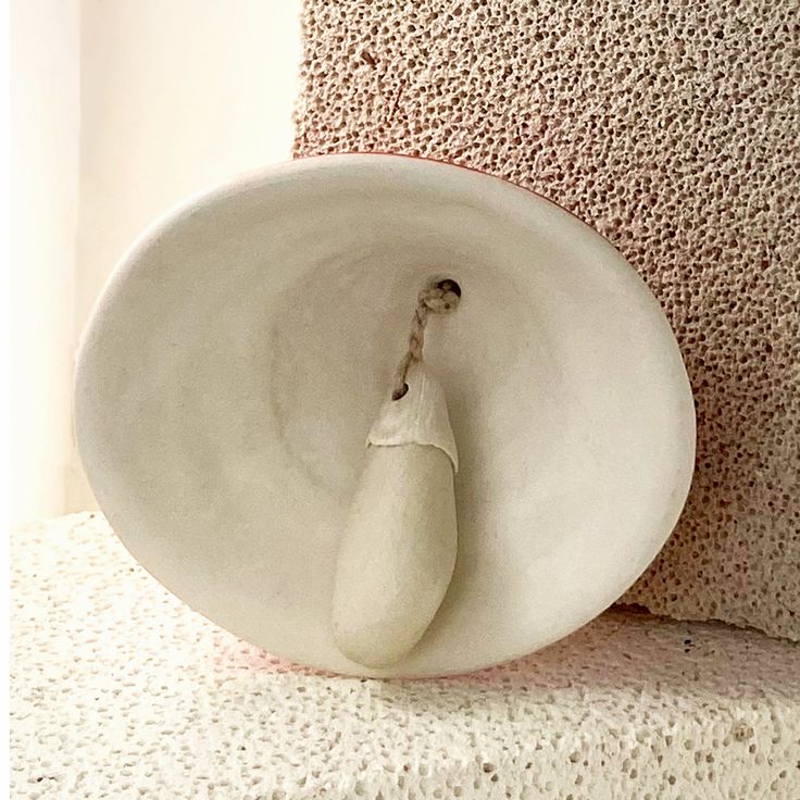 a white vase sitting on top of a floor next to a wall