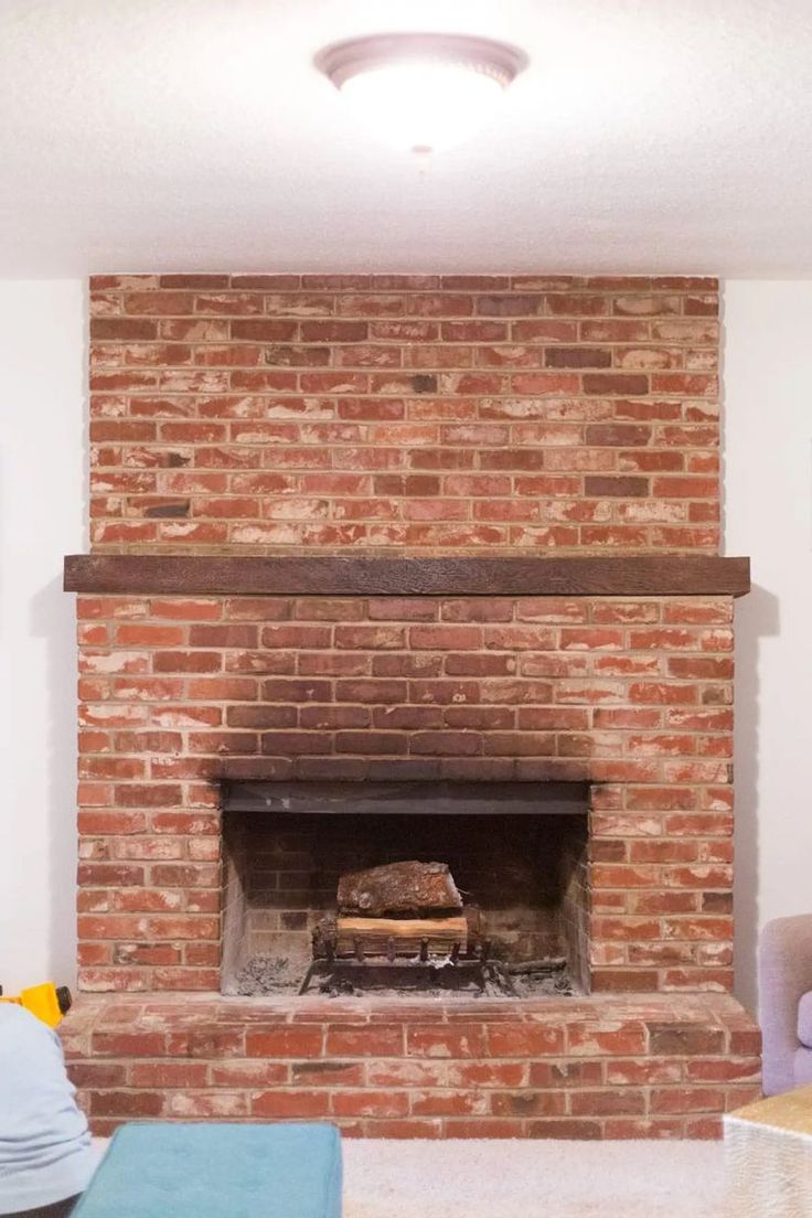 a living room with a fire place and couches in front of the brick fireplace