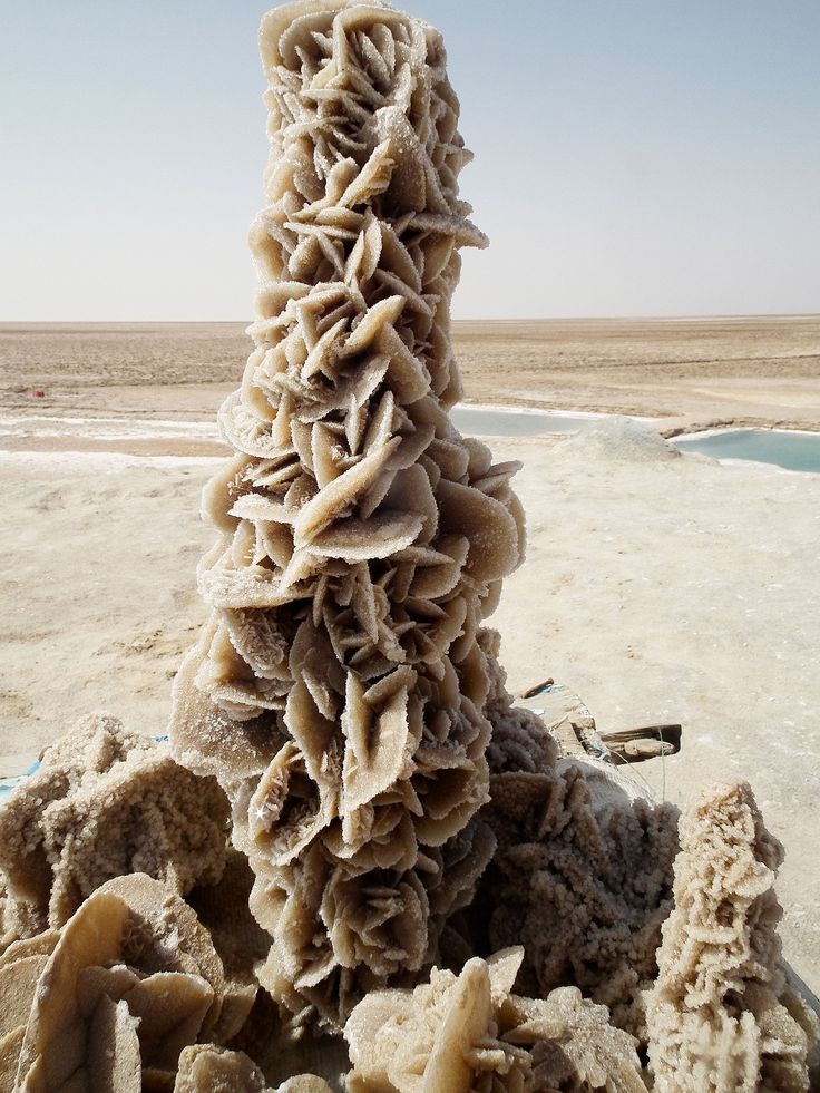 a large stack of rocks sitting on top of a sandy beach next to the ocean