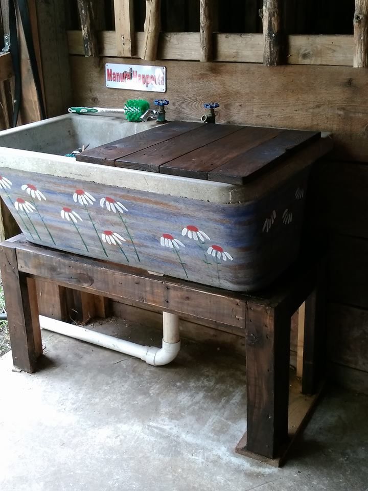 an old fashioned wooden sink with flowers painted on the side and pipes running underneath it