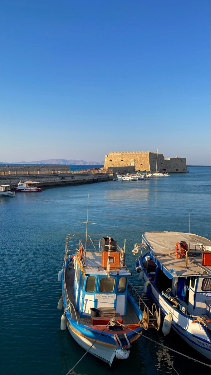 two boats are docked in the water next to an old castle