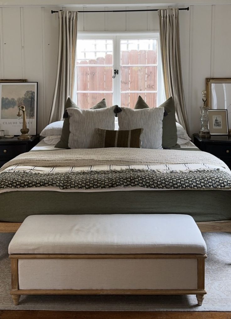 a bedroom with a bed, ottoman and window