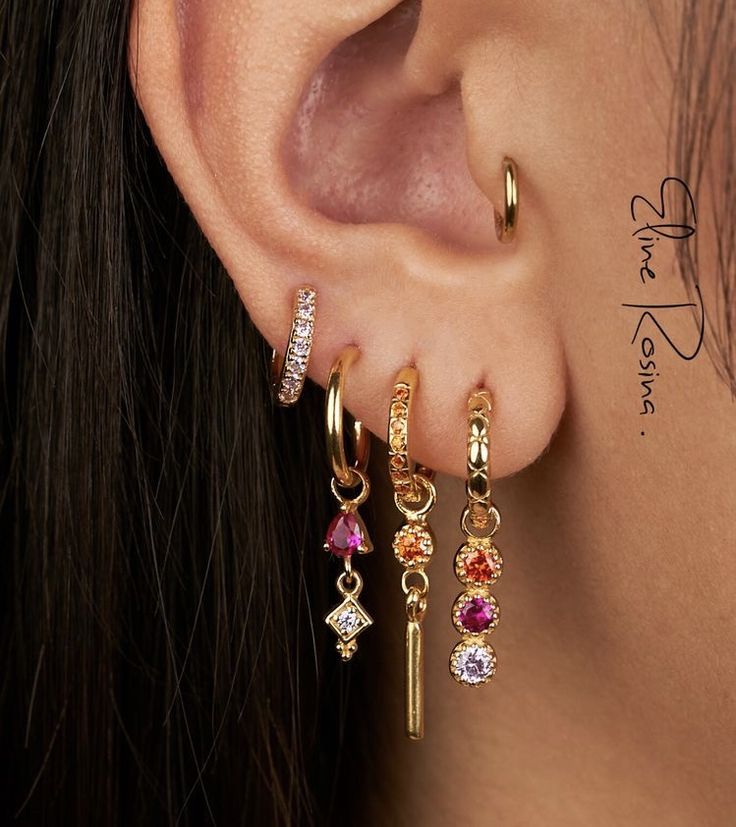 a close up of a person's ear with three different colored stones