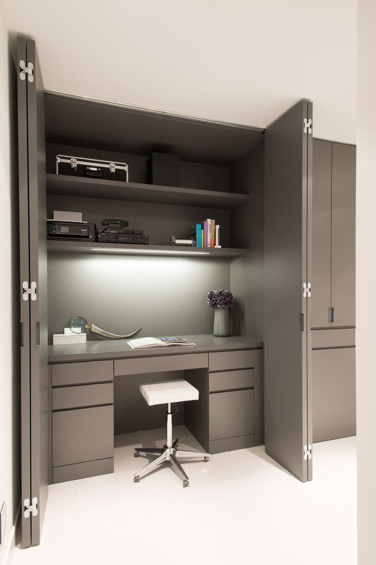 an office with gray cabinets and a white desk in the center is lit by a spot light