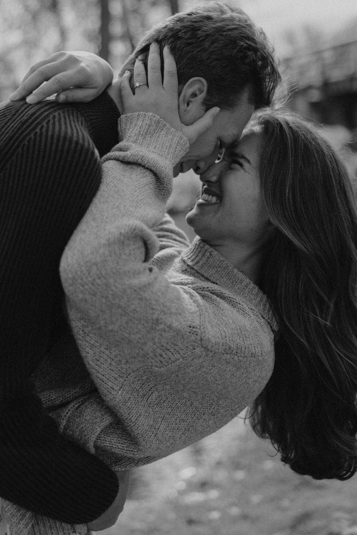 black and white photo of a couple kissing in the woods with trees in the background