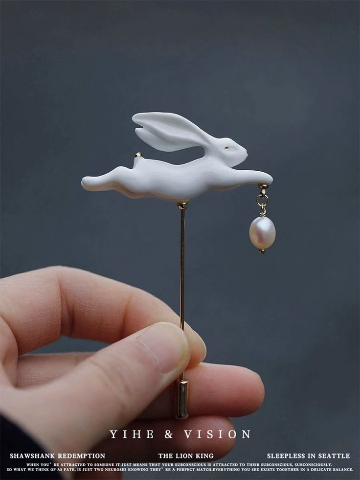 a person is holding a brooch with a white rabbit on it's back