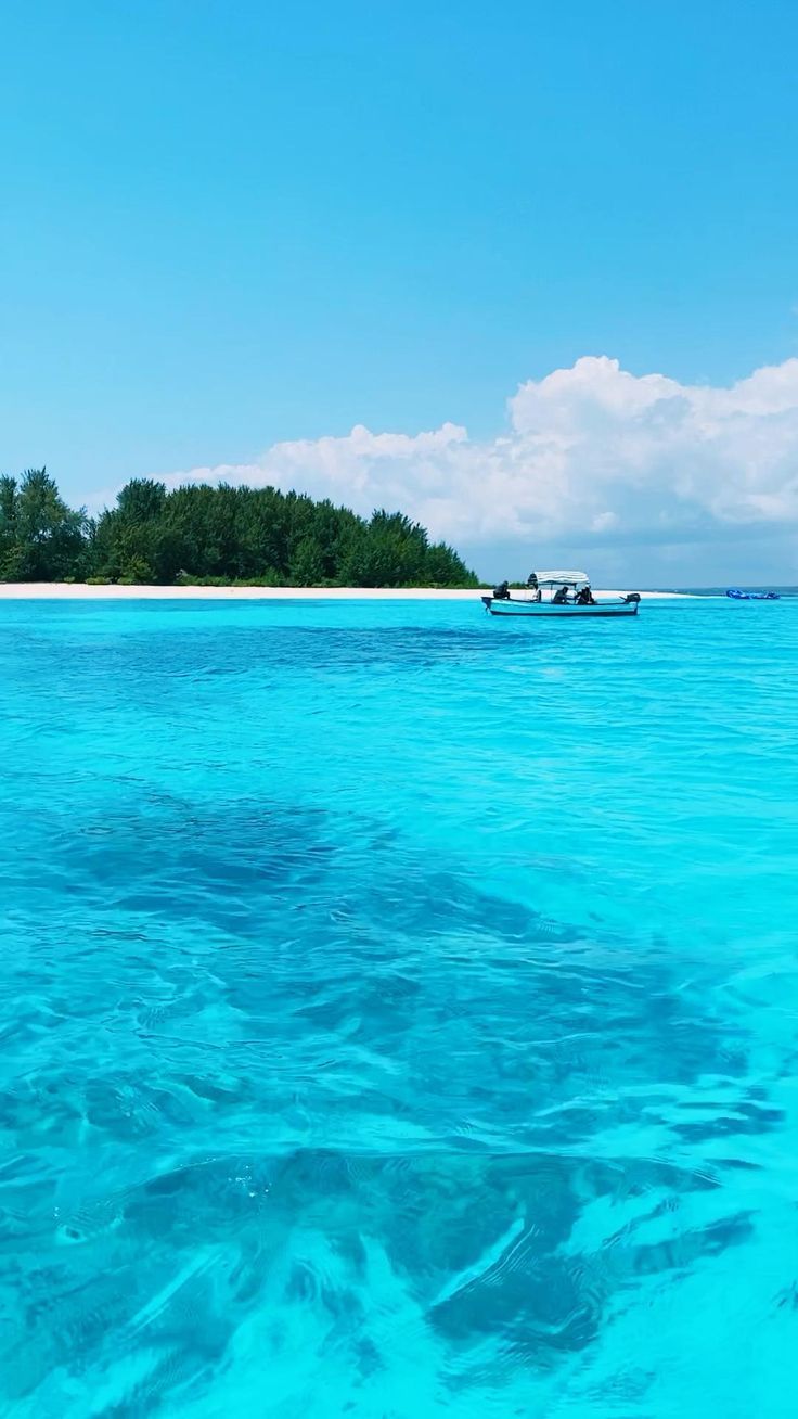 an island in the middle of the ocean with two boats on it's side