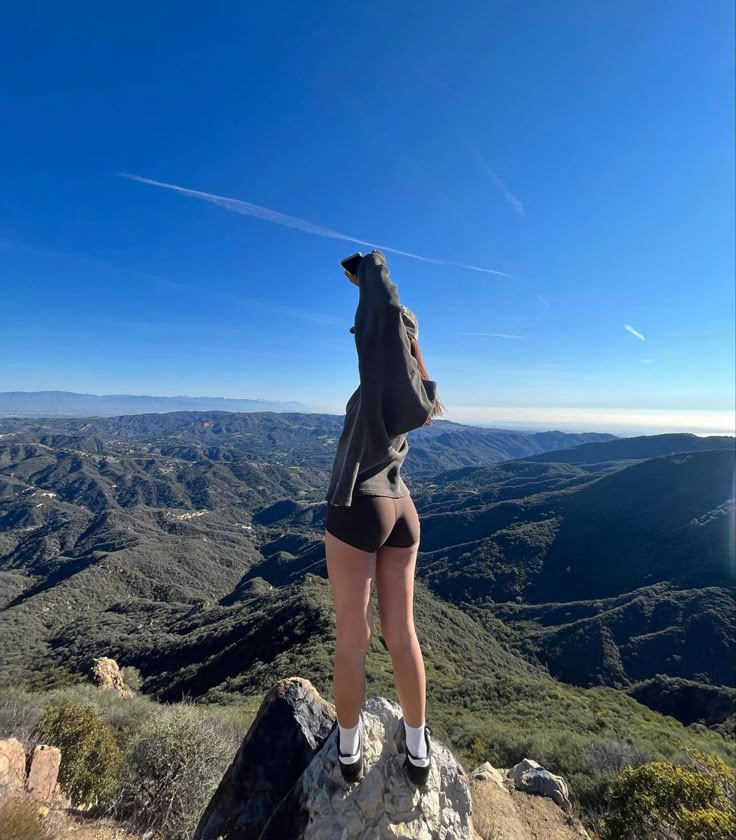 a woman standing on top of a rock with her back to the camera