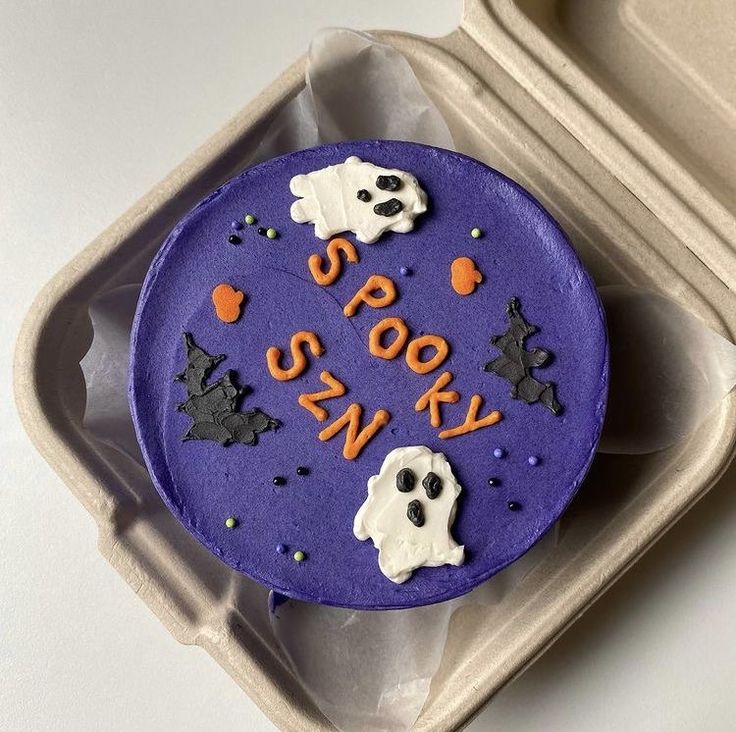 a purple cake with spooky words and ghost faces on it in a box