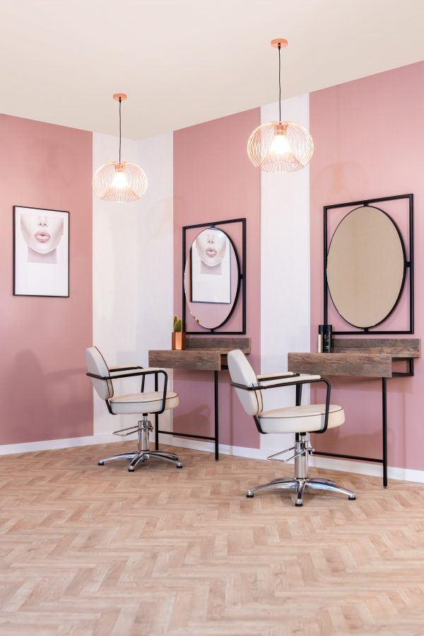 a room with two chairs and mirrors on the wall next to each other in front of pink walls