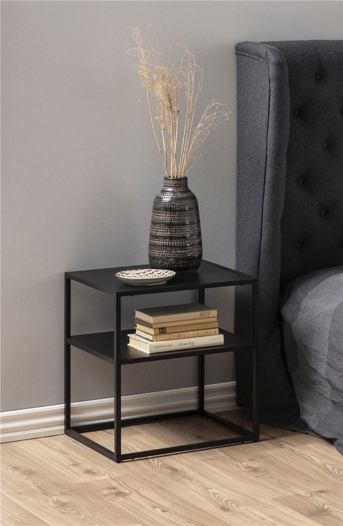 a black table with some books and a vase on it next to a gray chair