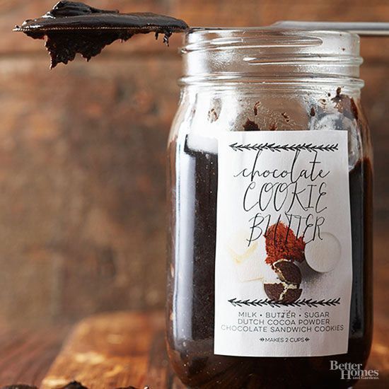 a glass jar filled with chocolate covered cookie dough next to a spoon on top of a wooden table