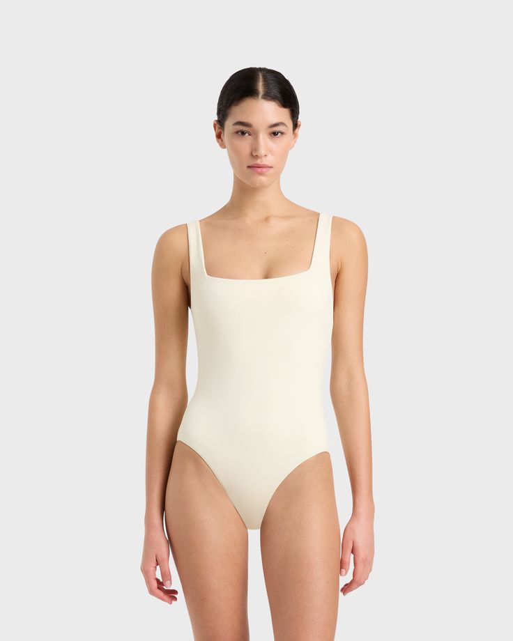 Margot one piece in Porcelain is a timeless classic swimsuit has an elegant square neckline front and back and invisible under-bust support. Self-lined in our ultra-soft Embodee™ fabric that has high shaping power, gently holding, shaping and enhancing the silhouette. To ensure the garment is opaque when wet, the front of the suit is a triple layer. A beautiful, classic one piece that will show off your summer tan and in a soft, matte fabric works perfectly as a body suit worn under skirts, shorts and pants. Luxury fabric sustainably made in Italy.Garment sustainably and ethically made in Australia. Solid Square Neck Swimwear With Moderate Back Coverage, Elegant Square Neck Stretch Swimwear, Chic White Second-skin Swimwear, White Square Neck Swimwear For Swimming, White Square Neck Swimwear For Beach, Elegant Swimwear With Square Neck And Adjustable Straps, Elegant Swimwear With Adjustable Straps And Square Neck, Classic Lined Swimwear, Elegant Square Neck Swimwear With Adjustable Straps