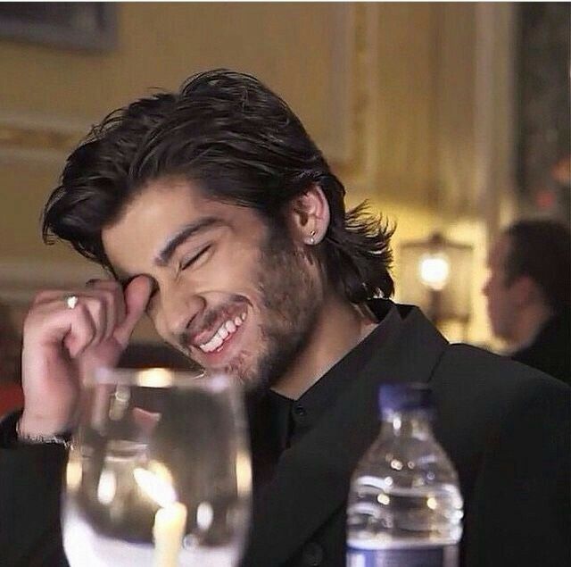 a man sitting at a table talking on a cell phone and smiling with his eyes closed