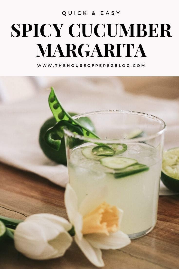 a close up of a drink on a table with flowers in the foreground and text overlay that reads quick & easy spicy cucumber margarita