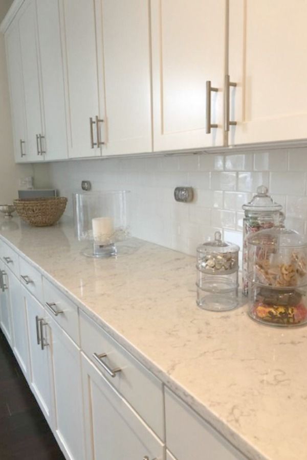 a kitchen with white cabinets and marble counter tops