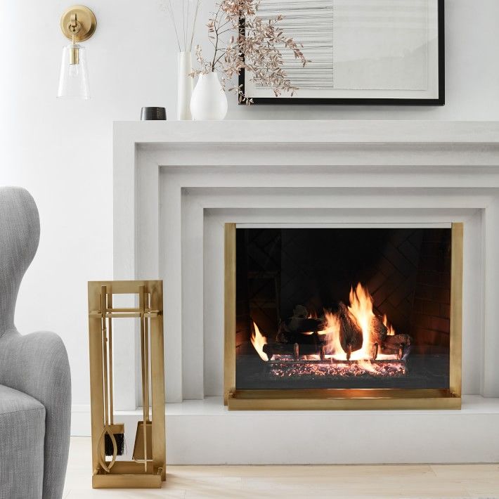 a fire place in a living room next to a gray chair and vases on the floor