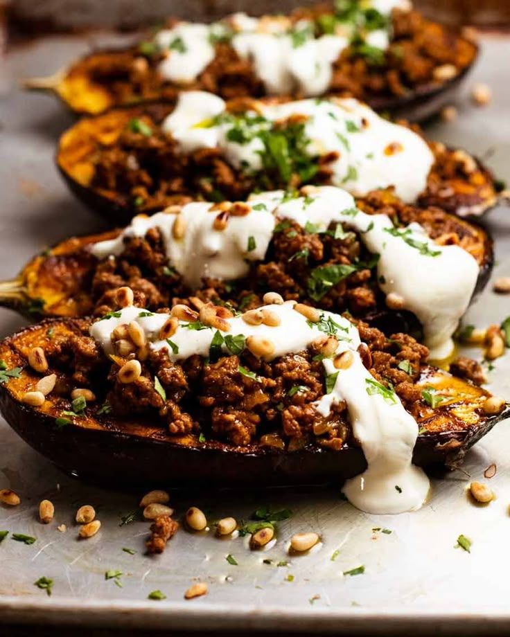 the stuffed eggplant is topped with ground meat and yogurt, sprinkled with parsley