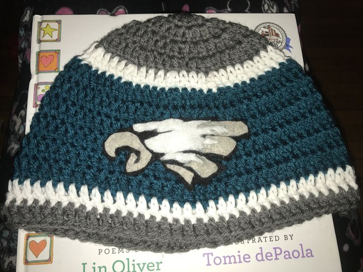 a crocheted hat with the philadelphia eagles logo on it sitting on top of a book