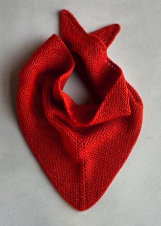 a red knitted scarf laying on top of a white surface