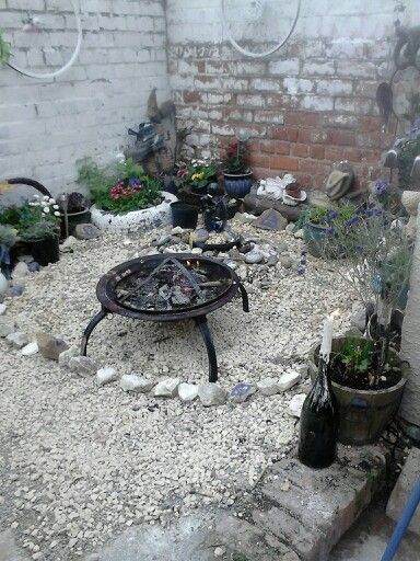 there is a fire pit in the middle of this garden area with rocks and gravel