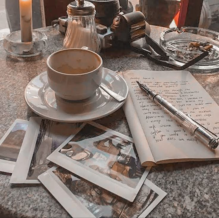 a table topped with photos and a cup of coffee next to an open notepad