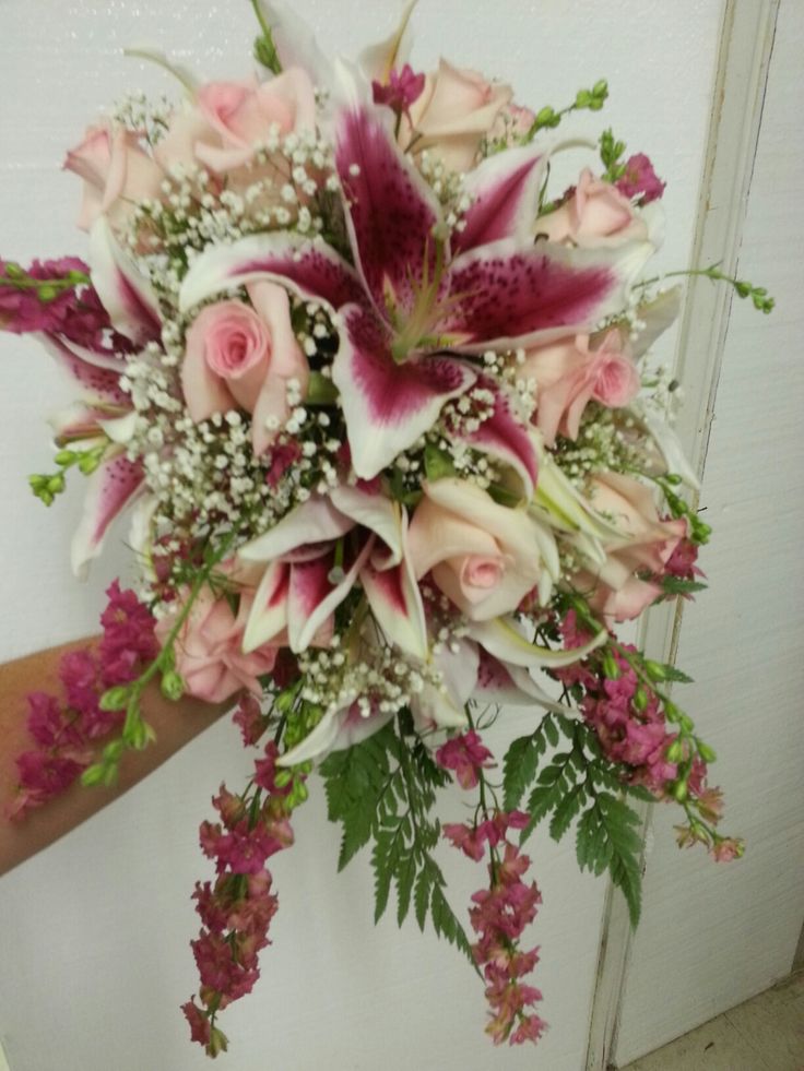 a bridal bouquet with pink and white flowers on the side of a door way