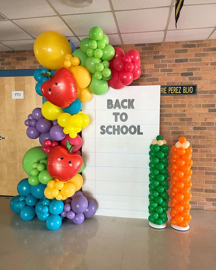 there are many balloons on the wall in front of this back to school sign that says back to school