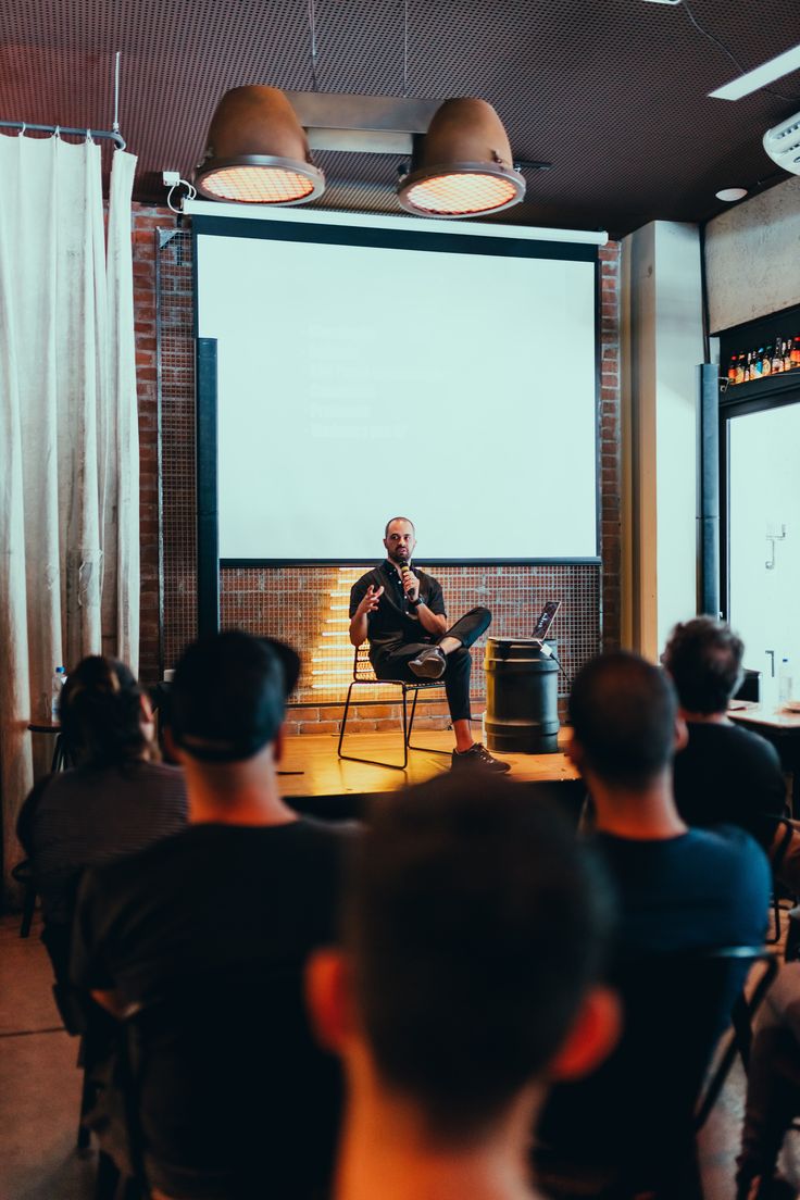 a man is sitting in front of a group of people watching something on the screen