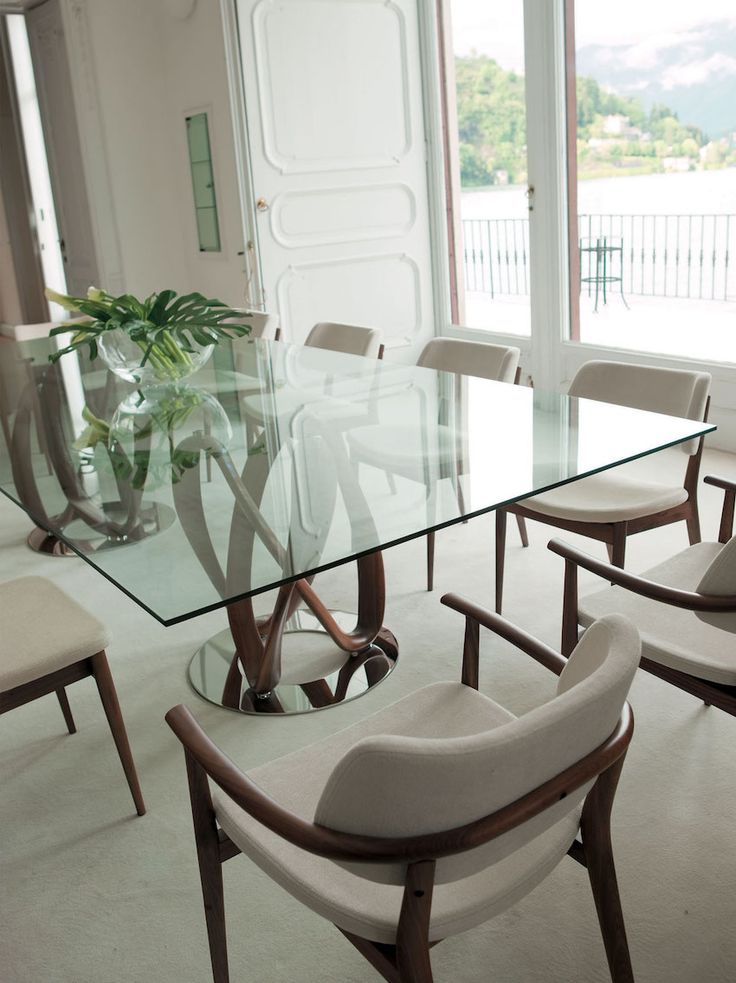 a glass table with chairs around it and a potted plant in the center on top