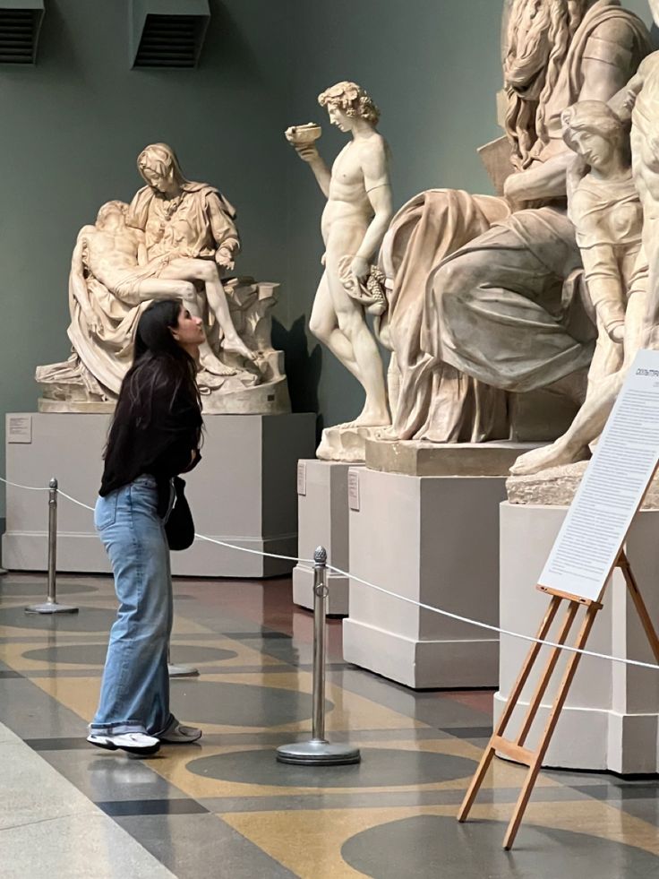 a woman is looking at statues in an art museum with easel on the floor