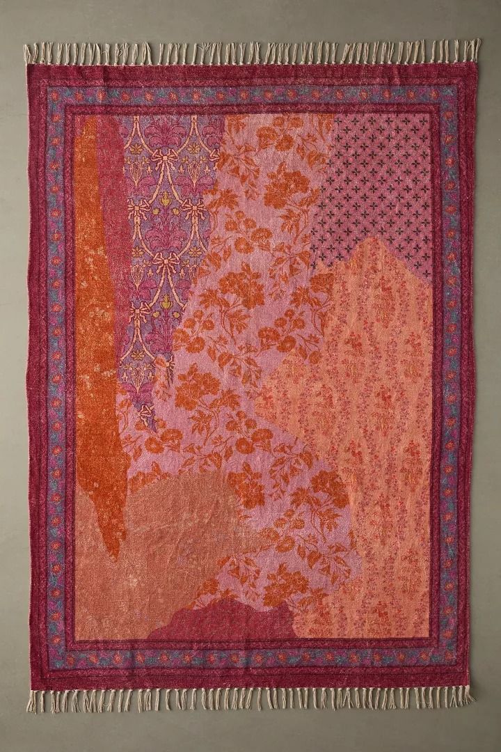 an orange and pink rug with fringes hanging on the wall